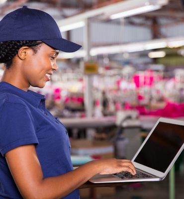 side view of clothing factory manager using laptop computer